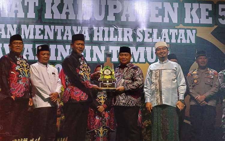 Bupati Kotawaringin Timur Halikinnor menyerahkan piala bergilir MTQ kabupaten kepada Camat Mentaya Hilir Selatan Syahrial selaku tuan rumah/ borneonews.co.id